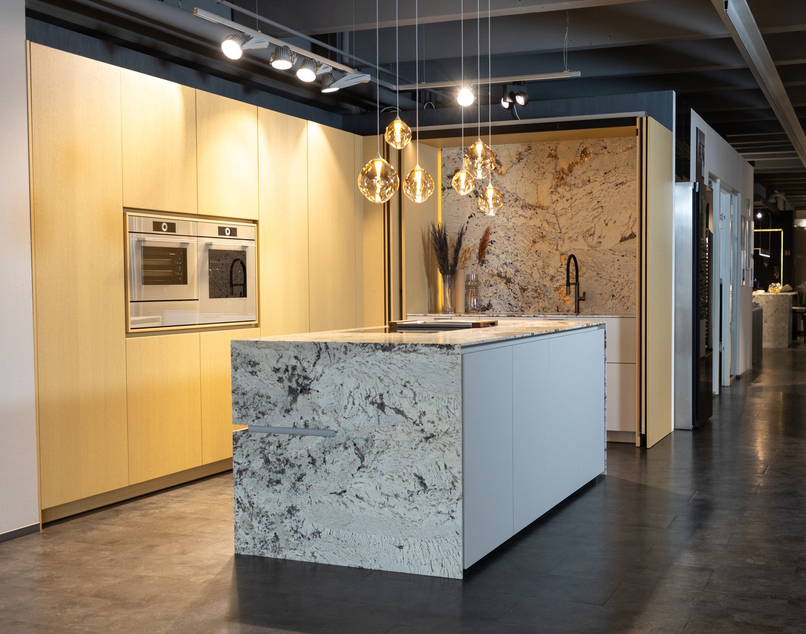Ausstellungsküche mit Steininsel und Pendelleuchten